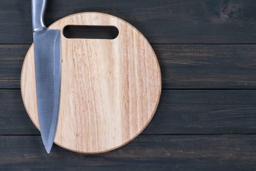 Close up kitchen knife and wooden round empty cutting board on a wooden table