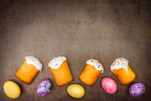 Easter cakes and Easter colored eggs on a dark background. Religious holiday of bright Easter.