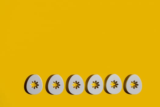 Some decorated wooden Easter eggs on a yellow surface