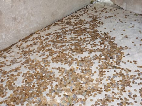 Coins on a concrete floor. Throwing for luck and success of coins in the holy site.