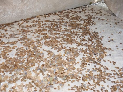 Coins on a concrete floor. Throwing for luck and success of coins in the holy site.