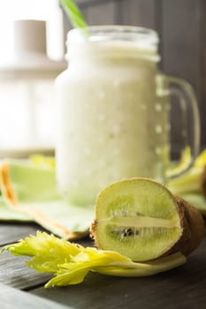 Fresh organic green smoothie with kiwi and celery, with glass jar and blender. Vertical image