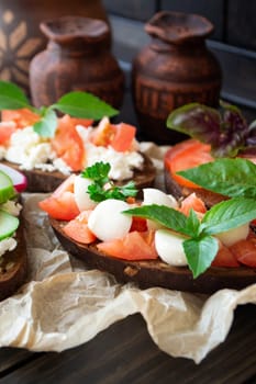Tomato and mozzarella sandwich with fresh basil leaves. Vertical image