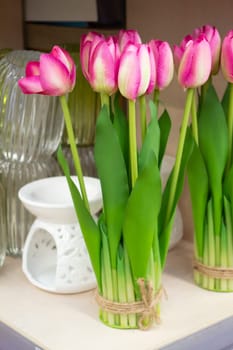 A round bright sunny pink fake tulips sitting on a rustic shabby chic wooden background