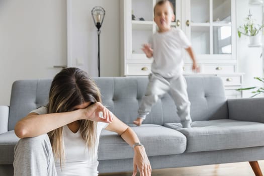 Hyperactive child and his tired and sad mother at home