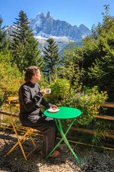 A young woman at an outdoor cafe  with a scenic view of the French Alps