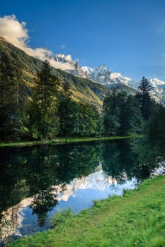 French Alps reflecting in still waters of the Arve River in the Chamonix Valley