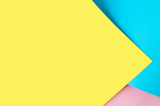 Background with multicolored sheets of paper placed geometrically randomly. Yellow, pink and blue paper sheets. High quality photo