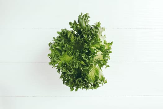 Flat lay with branch of fresh green salad leaves of lettuce salad on a white background. Healthy vegetarian eating concept. High quality photo