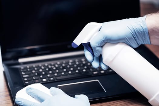 Coronavirus COVID-19 sanitize cleaning disinfection of work desk.Office sanitizing wipe wiping laptop with disinfecting wipes.