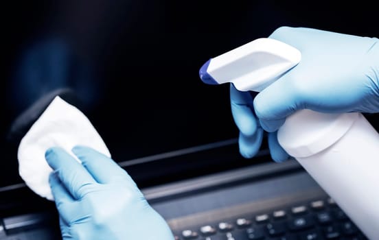 Coronavirus COVID-19 sanitize cleaning disinfection of work desk.Office sanitizing wipe wiping laptop with disinfecting wipes.