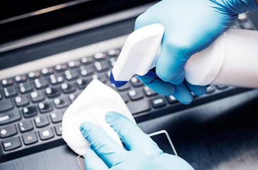 Coronavirus COVID-19 sanitize cleaning disinfection of work desk.Office sanitizing wipe wiping laptop with disinfecting wipes.