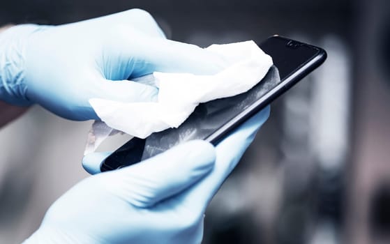 Coronavirus COVID-19 sanitize cleaning disinfection of smartphone.Office sanitizing wipe wiping phone with disinfecting wipes.