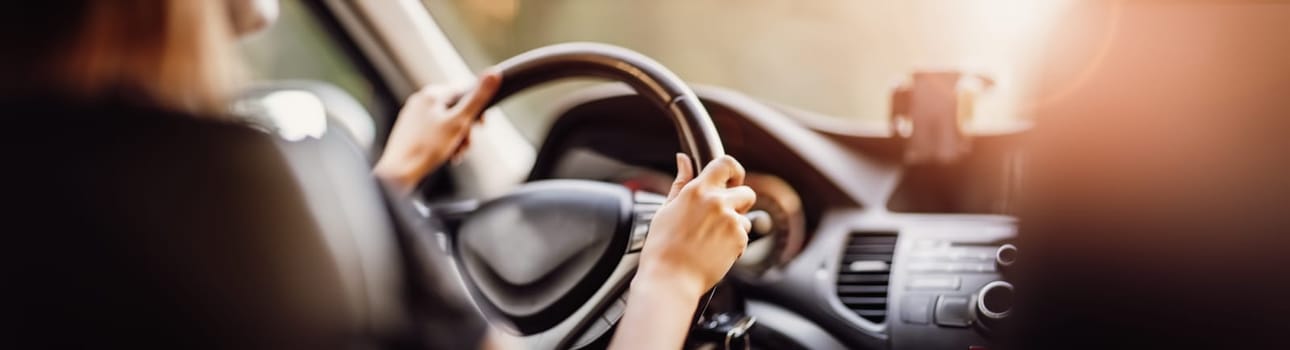 Driver driving a car on asphalt road in summer day at park. Woman at steering wheel