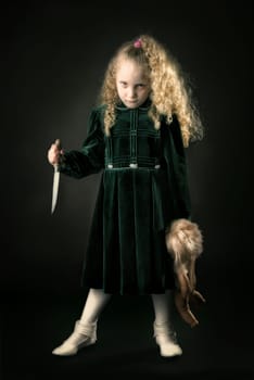 Scary young girl with a knife in a dark background