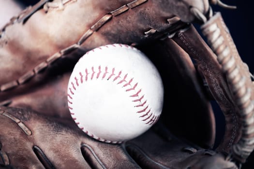 Close up image of an old used baseball and baseball glove.