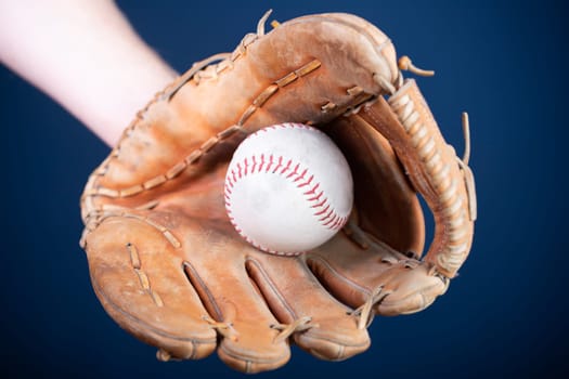 Close up image of an old used baseball and baseball glove.