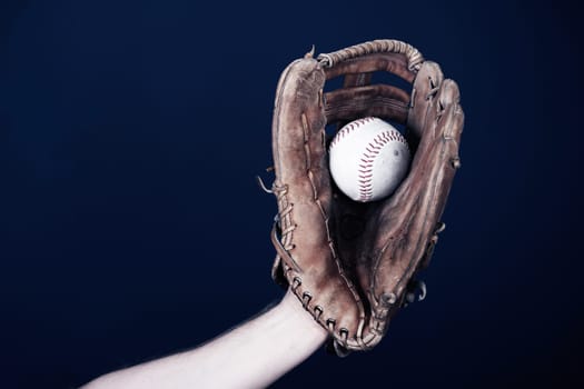 Close up image of an old used baseball and baseball glove.