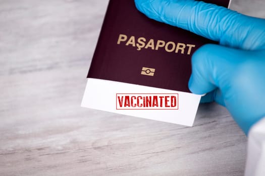 Doctor holding passport with VACCINATED sign. Immunity passport, risk-free certificate concept.