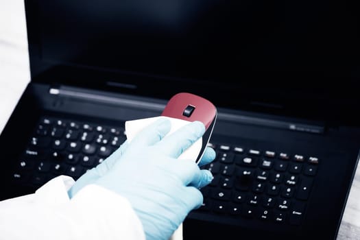Office sanitizing wiping mouse with disinfectant. Coronavirus COVID-19 sanitize cleaning, disinfection of work desk.