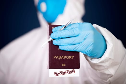 Doctor holding passport with VACCINATED sign and vaccine. Immunity passport, risk-free certificate concept.