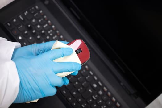 Office sanitizing wiping mouse with disinfectant. Coronavirus COVID-19 sanitize cleaning, disinfection of work desk.