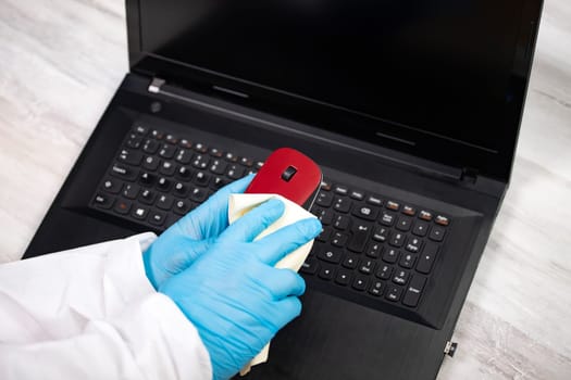 Office sanitizing wiping mouse with disinfectant. Coronavirus COVID-19 sanitize cleaning, disinfection of work desk.