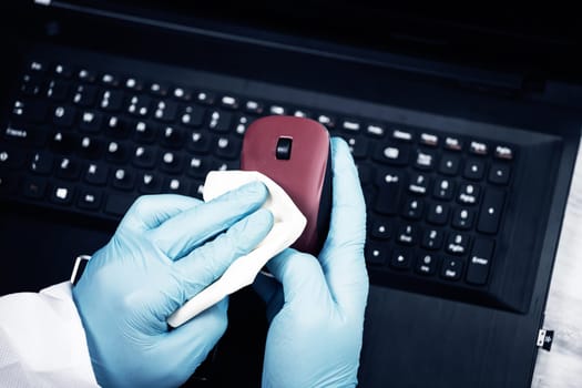 Office sanitizing wiping mouse with disinfectant. Coronavirus COVID-19 sanitize cleaning, disinfection of work desk.