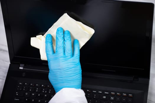 Office sanitizing wiping laptop with disinfectant. Coronavirus COVID-19 sanitize cleaning, disinfection of work desk.
