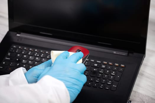 Office sanitizing wiping mouse with disinfectant. Coronavirus COVID-19 sanitize cleaning, disinfection of work desk.