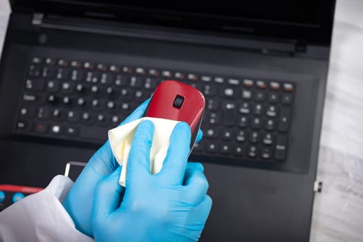 Office sanitizing wiping mouse with disinfectant. Coronavirus COVID-19 sanitize cleaning, disinfection of work desk.