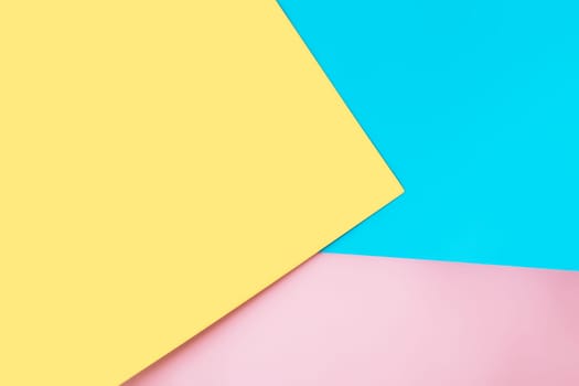 Background with multicolored sheets of paper placed geometrically randomly. Yellow, pink and blue paper sheets. High quality photo