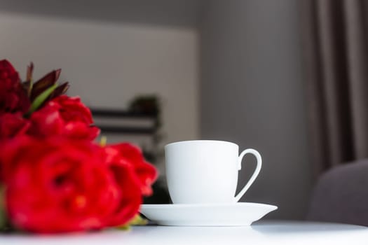 Red tulips bouquete on table, white coffee cup. Concept for greeting card for mothers day, international womans day or valentines day concept, birthday greeting concept