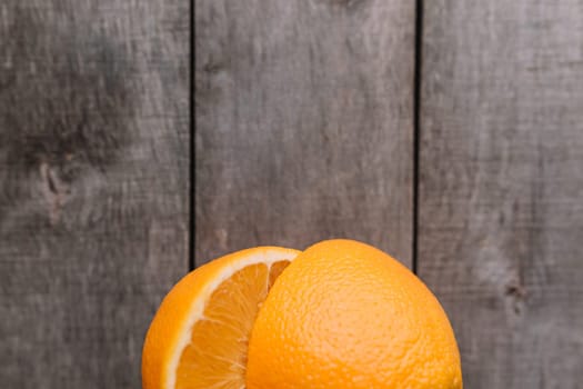 Flat lay with fresh ripe sliced halves of orange fruit on gray wooden background. Orange pulp and green leaves. Tropic food concept. Healthy eating concept. High quality photo