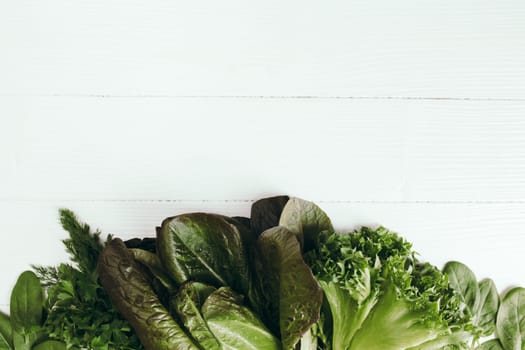 Flat lay with fresh green salad leaves of spinach, lettuce, romaine on white background. Healthy vegetarian eating concept. High quality photo