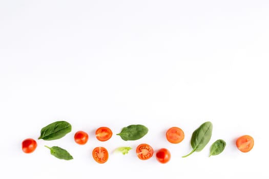 Flat lay with red cherry tomatoes and green spinach leaves on a white background. Healthy eating concept. High quality photo