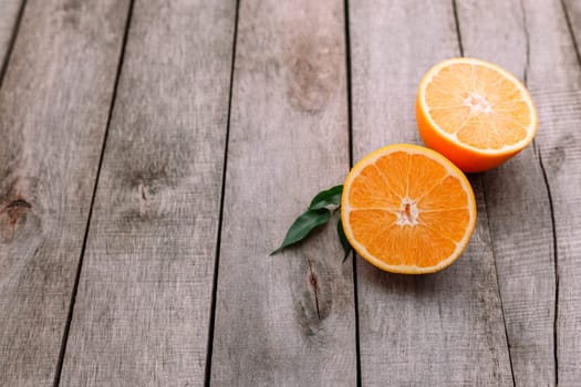 Flat lay with fresh ripe sliced halves of orange fruit on gray wooden background. Orange pulp and green leaves. Tropic food concept. Healthy eating concept. High quality photo