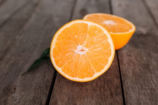 Flat lay with fresh ripe sliced halves of orange fruit on gray wooden background. Orange pulp and green leaves. Tropic food concept. Healthy eating concept. High quality photo