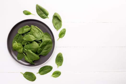 Bowl with fresh green salad leaves of spinach on a white background. Healthy vegetarian eating concept. High quality photo