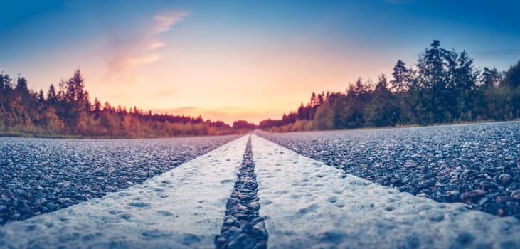 Black road panorama on sunny summer evening. Close-up roadway with white dividing lines.