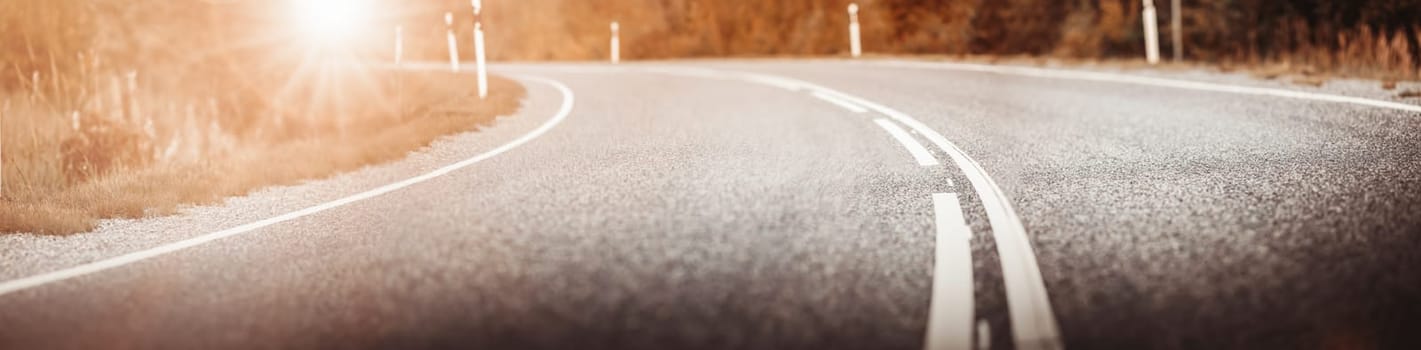 Asphalt road panorama in countryside on sunset in summer. Route with white dividing lines in beautiful nature landscape.