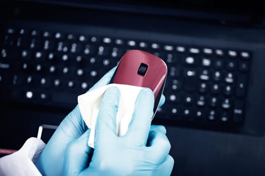 Office sanitizing wiping mouse with disinfectant. Coronavirus COVID-19 sanitize cleaning, disinfection of work desk.