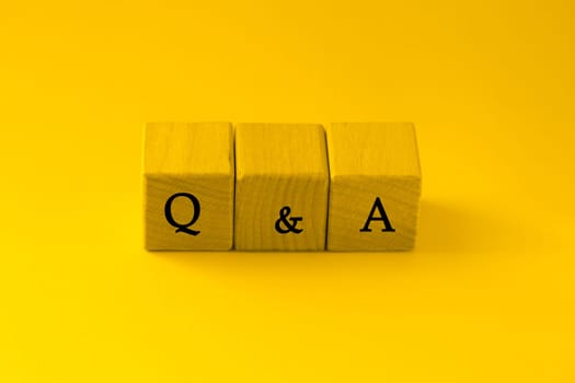 Color of the year Illuminating. Wooden blocks with the word FAQ - frequently asked questions. Instructions and rules on Internet sites.