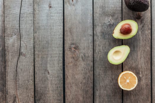 Healthy eating concept flat lay. Mediterranean diet, wooden background with avocado halves, whole avocado, avocado kernel, lemon half. Vegetarian food. Healthy food concept. Organic food