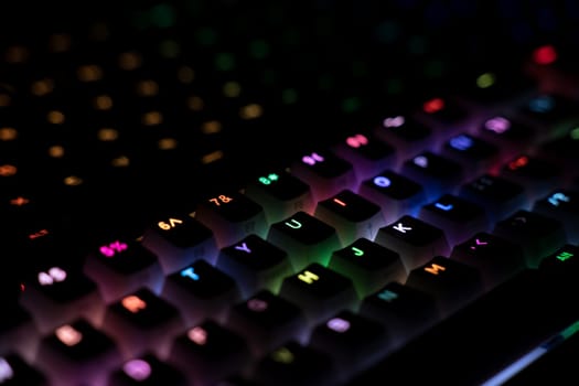 top view detail closeup of two illuminated mechanical gaming RGB keyboard with keycaps lighting up in different colors in the dark