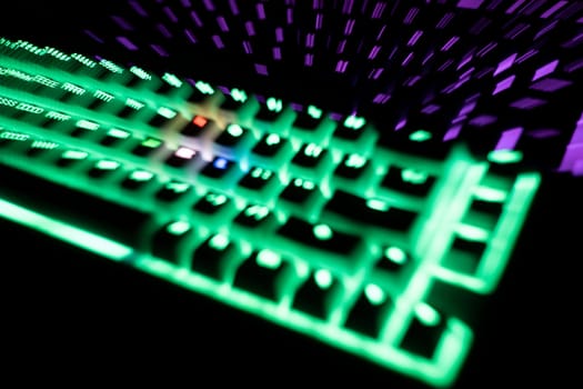 out of focus top view detail closeup of two illuminated mechanical gaming RGB keyboard with keycaps lighting up in different colors in the dark