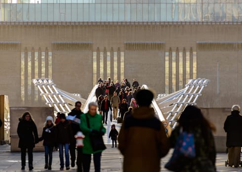 LONDON, UK - CIRCA JANUARY 2013: People on the Millennium Bridge. The Millennium Bridge is a steel suspension footbridge over the Thames River for pedestrians.