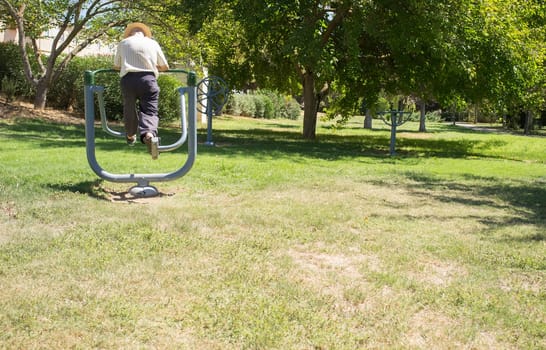Elder man make exercises at Outdoor Gym Park. Healthy active ageing concept