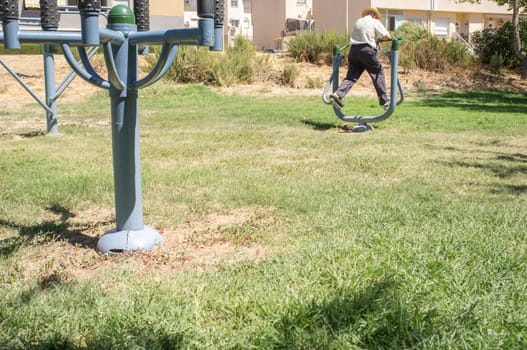 Elder man make exercises at Outdoor Gym Park. Healthy active ageing concept