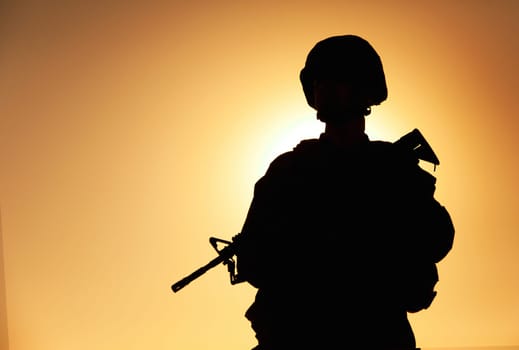 Half-length silhouette of army infantry shooter, special operations forces soldier, Marines rider in combat helmet and ammunition, armed with service rifle standing on background of sunset sky